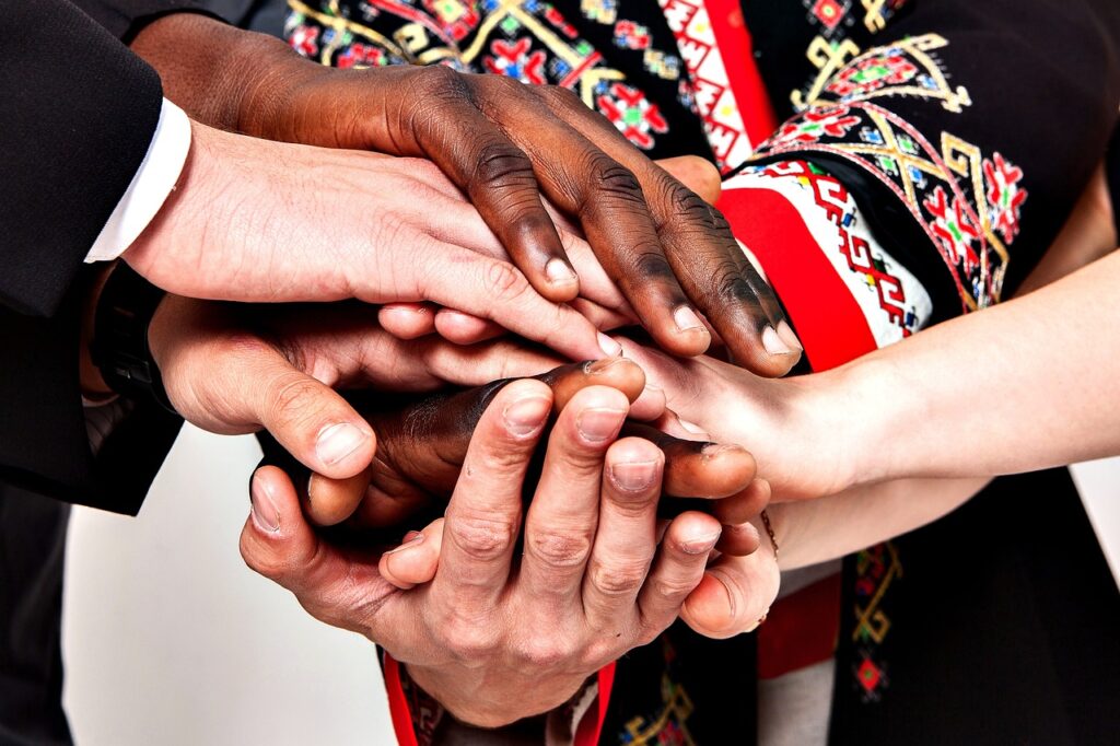 Dłonie kobiet i mężczyzn o różnym kolorze skóry ułożonee jedna na drugiej